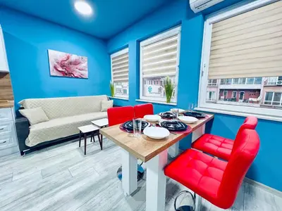 a living room with blue walls and a table and red chairs at NJ Deluxe rooms in Varna City