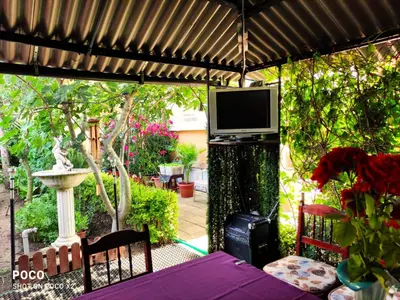 a patio with a table and a television on a pergola at Доли in Pomorie