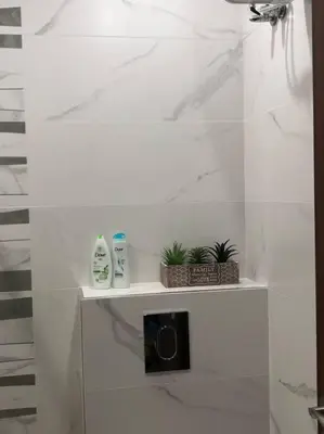 a white bathroom with two bottles of soap and two plants at *HOT* Main Square Brand New Luxury Apartment in Burgas City