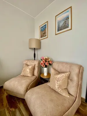 a living room with two chairs and a table with flowers at K&K Sunset in Burgas City