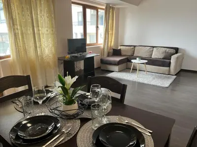 a dining room with a table and a living room at Lazur Apartment AQUA in Burgas City