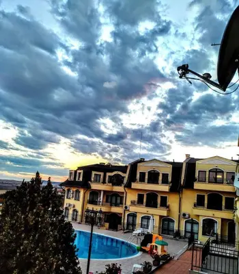 a building with a pool and a cloudy sky at Apartament Morela in Sunny Beach