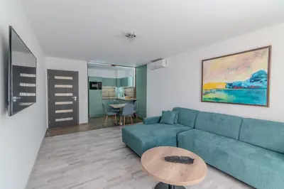 a living room with a blue couch and a table at Sea Twins Luxury Aparthotel - 150 m from the beach in Sunny Beach