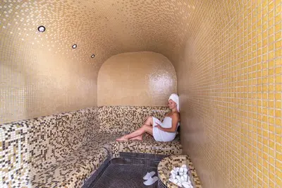 a woman sitting in a bath tub in a room at Sea Twins Luxury Aparthotel - 150 m from the beach in Sunny Beach