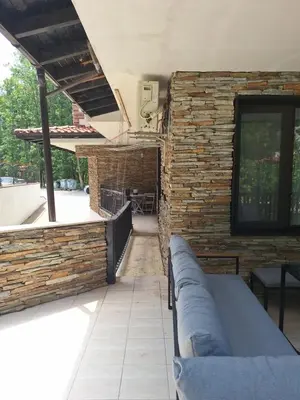 a patio with a couch and a brick wall at Green Paradise apartman 105 in Primorsko