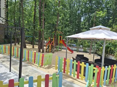 a playground with a colorful fence and an umbrella at Green Paradise apartman 105 in Primorsko