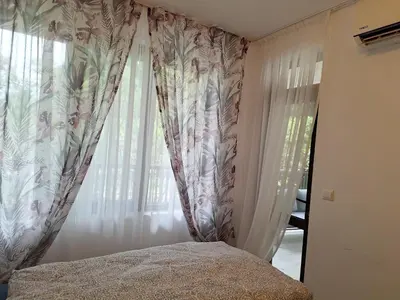 a bedroom with a bed and a window with curtains at Green Paradise apartman 105 in Primorsko