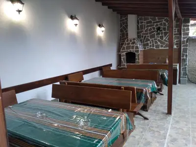 a room with several tables and benches with a fireplace at Лятна вила Генчеви град Обзор in Obzor