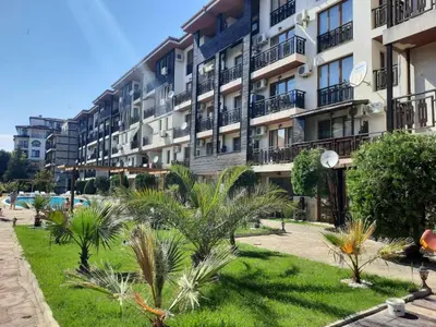 a large apartment building with palm trees in front of it at Апатаменти за гости Sunshine и Glory in Sveti Vlas