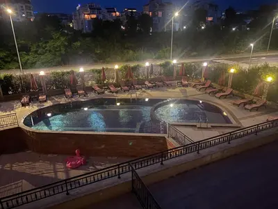 a swimming pool at night with chairs and tables at River Park Studio in Sunny Beach