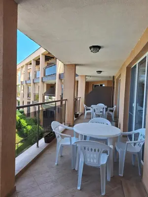 a balcony with white tables and chairs and a building at Созополи Хилс A11 in Sozopol