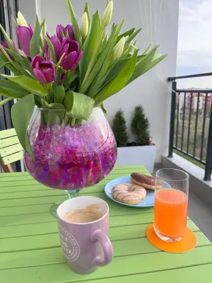 a table with a vase of flowers and a cup of coffee at Boutique Sozopol in Sozopol