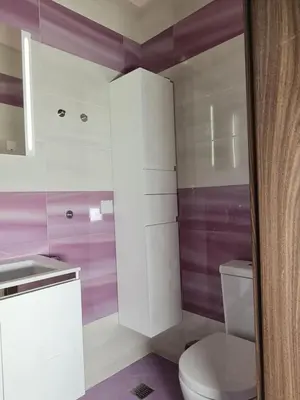 a bathroom with a white toilet and purple walls at Луксозен апартамент в Резиденция Лазурен бряг in Burgas City