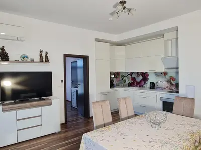 a kitchen and dining room with a table and a television at Луксозен апартамент в Резиденция Лазурен бряг in Burgas City