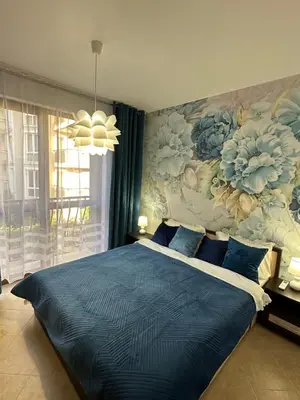 a bedroom with a blue bed with a floral wall at Cascadas family apartamant 2 in Sunny Beach