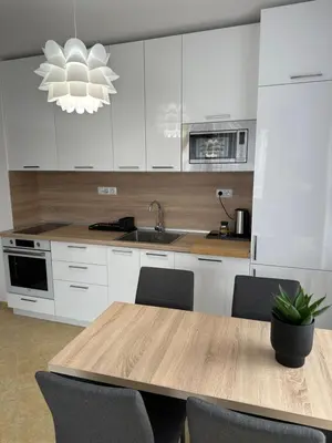 a kitchen with white cabinets and a wooden table with chairs at Cascadas family apartamant 2 in Sunny Beach