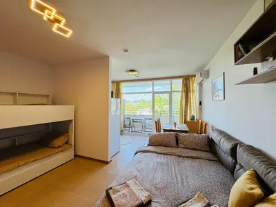 a living room with a leather couch and a dining room at GRAND KAMELIA B 2,8 Large Studio Sunny Beach in Sunny Beach