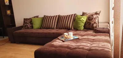 a brown couch with green pillows and a tray on it at Sunny Day Pomorie in Pomorie