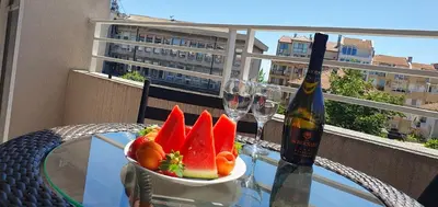 a bowl of fruit on a glass table with a bottle of wine at Sunny Day Pomorie in Pomorie