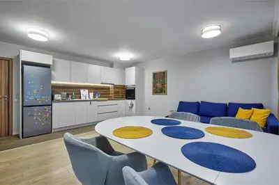a dining room with a white table and blue chairs at The little things apt - Parking & Own EV Chаrgеr by Flat Mаnаger in Burgas City