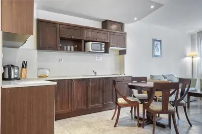 a kitchen with wooden cabinets and a table with chairs at The Cliff Hotel and Holiday Apartments by Flat Mаnаger in Obzor