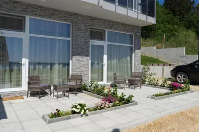 a patio with chairs and flowers in front of a building at Paradise View Rooms in Shkorpilovtsi