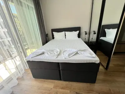 a bedroom with a bed with white sheets and a mirror at Double studio Petra B2-5 in Byala