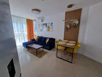 a living room with a blue couch and a table at Апартамент МеГи in Burgas City