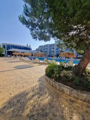 a beach with chairs and umbrellas and a building at Апартамент МеГи in Burgas City