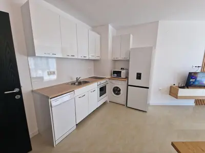 a kitchen with white cabinets and a washer and dryer at Апартамент МеГи in Burgas City