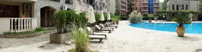 a row of chairs next to a pool in a building at Menada Kalia Apartments in Sunny Beach