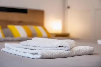 three white towels stacked on a table with yellow chairs at Cozy Central Apartment Varna & Parking - subject to availability in Varna City