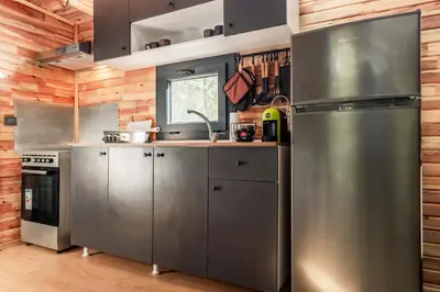 a kitchen with stainless steel appliances and wooden walls at Lion's Forest in Atiya