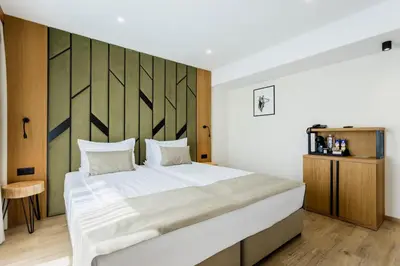 a bedroom with a large bed and a wooden wall at Natura All Seasons Boutique Hotel in Burgas City
