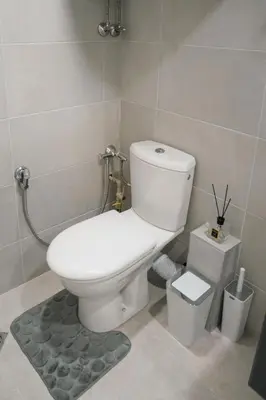 a bathroom with a white toilet and a trash can at Стилен и уютен апартамент в центъра Варна in Varna City