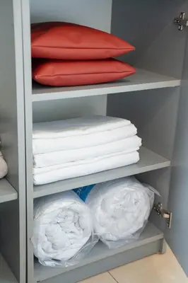 a closet filled with white towels and red pillows at Стилен и уютен апартамент в центъра Варна in Varna City