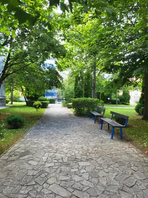 two benches sitting on a path in a park at Апартамент Бриджит Слънчев бряг in Sunny Beach