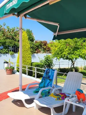 two chairs sitting under an umbrella on a patio at Апартамент Бриджит Слънчев бряг in Sunny Beach