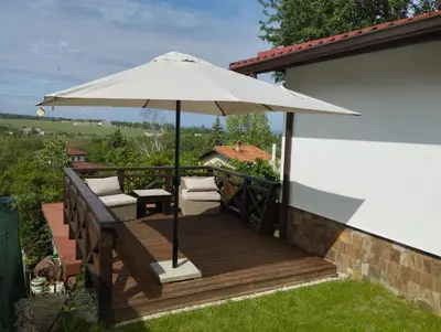 a wooden deck with an umbrella and two chairs at Горе на вилата in Shkorpilovtsi