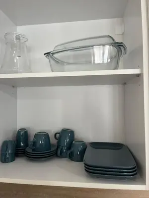 a shelf with blue cups and plates and a glass bowl at Elizi summer house in Varna South Bay Beach in Varna City