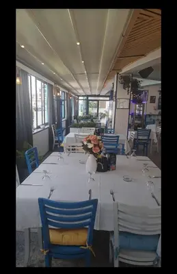 a long table with white tables and blue chairs at Семеен Хотел ''Кораб Ренеса'' in Ravda