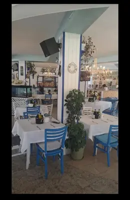 a restaurant with white tables and blue chairs at Семеен Хотел ''Кораб Ренеса'' in Ravda