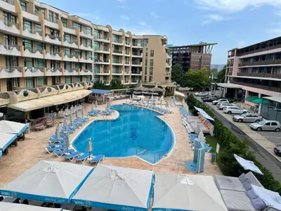 a swimming pool with chairs and umbrellas in front of a hotel at Grenada - Apartments by the beach in Sunny Beach