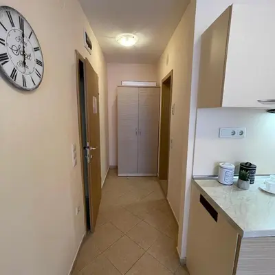 a kitchen with a clock on the wall and a hallway at Royal Sun - Premium Apartments in Sunny Beach