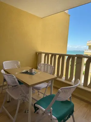 a table and chairs with a table and a balcony at Gold Coast SP apartments in Burgas City