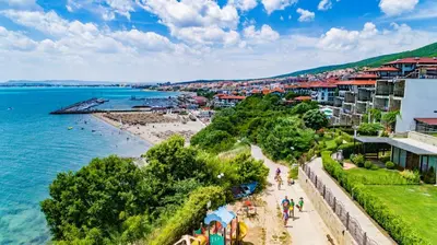 a group of people walking along a beach next to the water at MONASTERY Seafront Apartments in Sveti Vlas