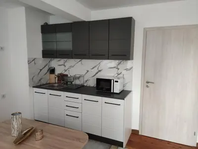 a kitchen with white cabinets and a black counter top at rozi in Burgas City