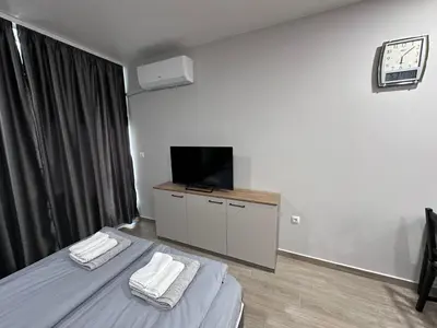a hotel room with two beds and a flat screen tv at Студио Комфорт Бургас Център in Burgas City