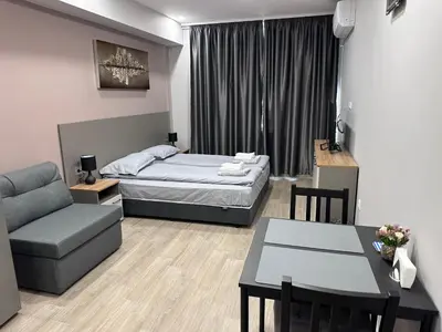 a bedroom with a bed and a couch and a table at Студио Комфорт Бургас Център in Burgas City