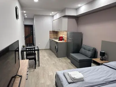 a bedroom with a bed and a table and a kitchen at Студио Комфорт Бургас Център in Burgas City